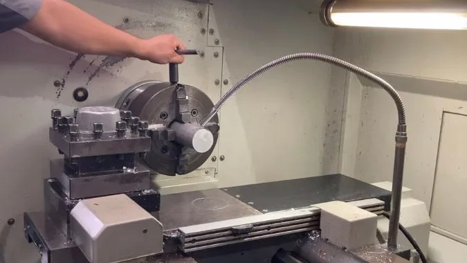 A machinist adjusting a 4-jaw chuck clamping the workpiece