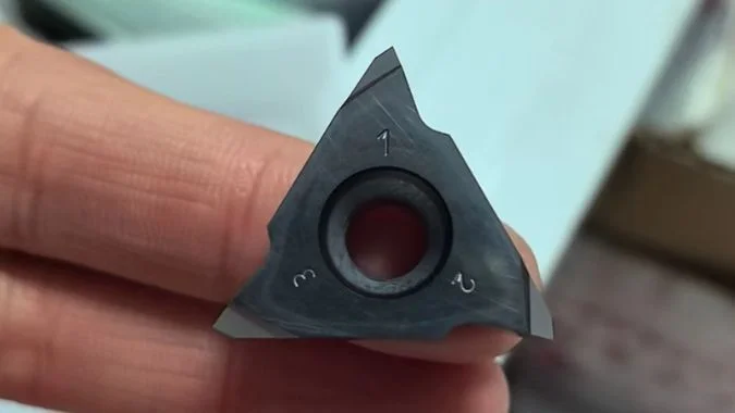 Close-up of a triangular thread whirling insert for cutting-edge wear inspection